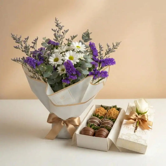 Ramo de flores con margaritas blancas y estatice morado junto a una caja de fresas cubiertas de chocolate de Fruit Santé.