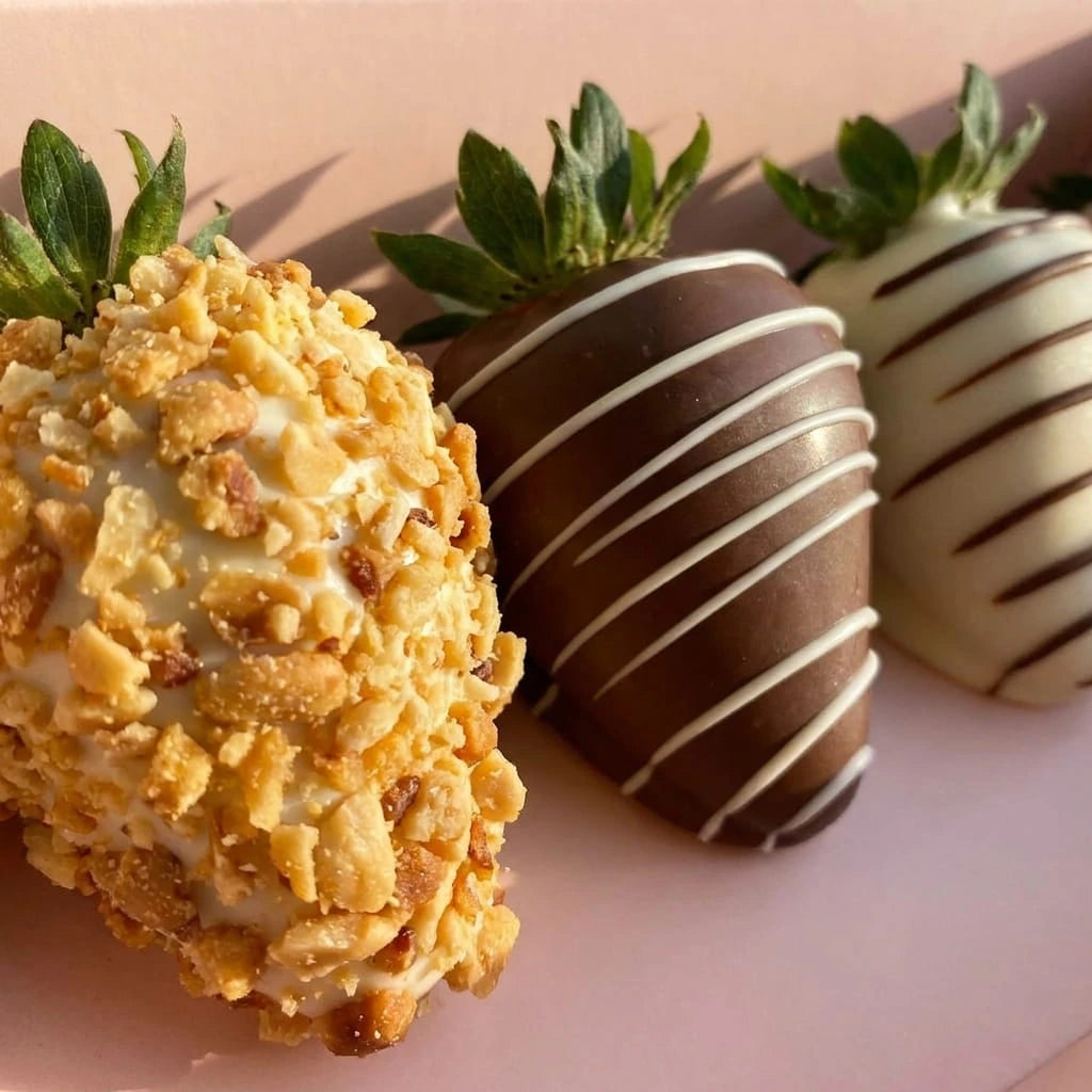 Detalle de fresas premium con chocolate oscuro, chocolate blanco y maní tostado decoradas a mano