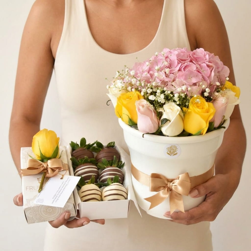 Persona sosteniendo el arreglo de flores pastel con la caja de fresas con chocolate, referencia de tamaño
