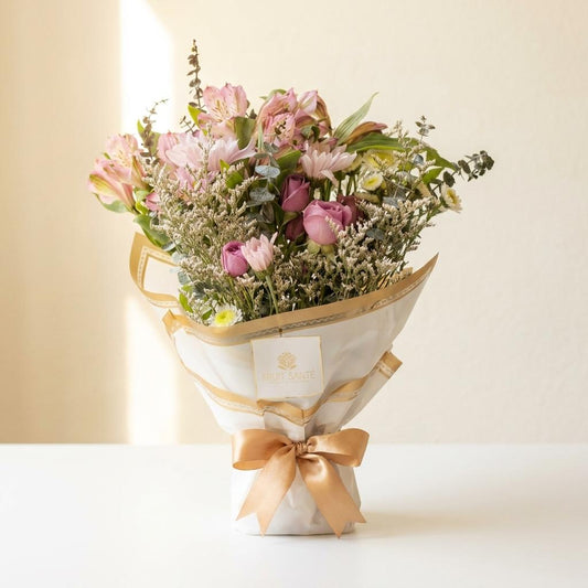 Bouquet de astromelias rosadas, rosas y eucalipto envuelto en papel blanco con lazo dorado Fruit Santé Bogotá
