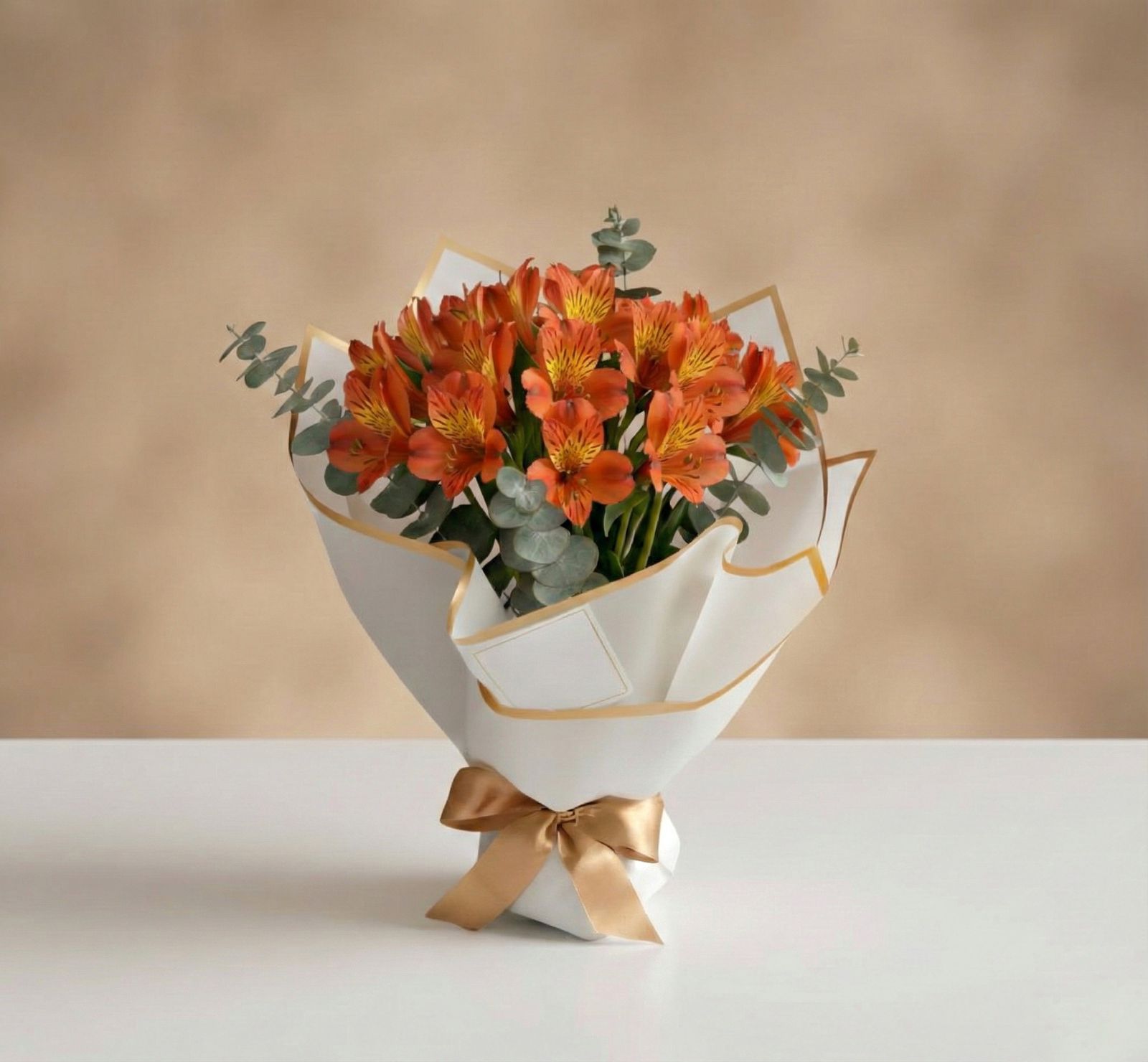 Bouquet de alstroemerias naranjas con eucalipto en empaque blanco minimalista con lazo dorado – Fruit Santé Bogotá