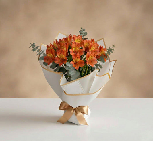 Bouquet de alstroemerias naranjas con eucalipto en empaque blanco minimalista con lazo dorado – Fruit Santé Bogotá