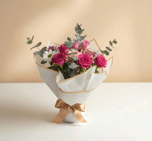 Bouquet de rosas fucsia y pastel con margaritas blancas y eucalipto en empaque blanco minimalista con lazo dorado – Fruit Santé Bogotá