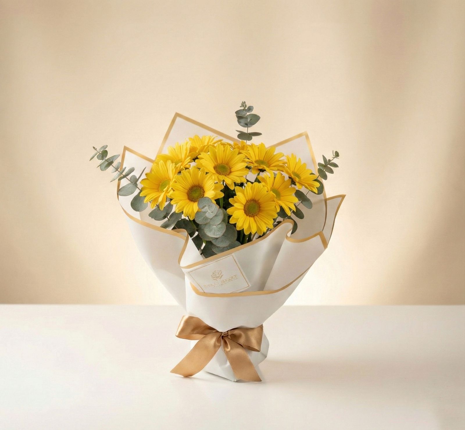 Bouquet de margaritas amarillas con eucalipto en empaque blanco minimalista con lazo dorado – Fruit Santé Bogotá