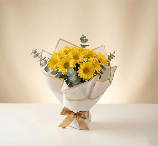 Bouquet de margaritas amarillas con eucalipto en empaque blanco minimalista con lazo dorado – Fruit Santé Bogotá